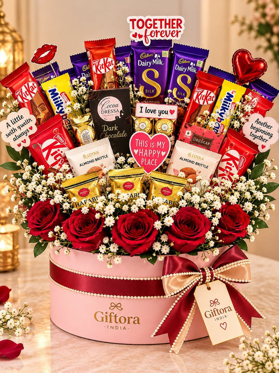 Assorted chocolates and red roses arranged in a pink Giftora India gift box